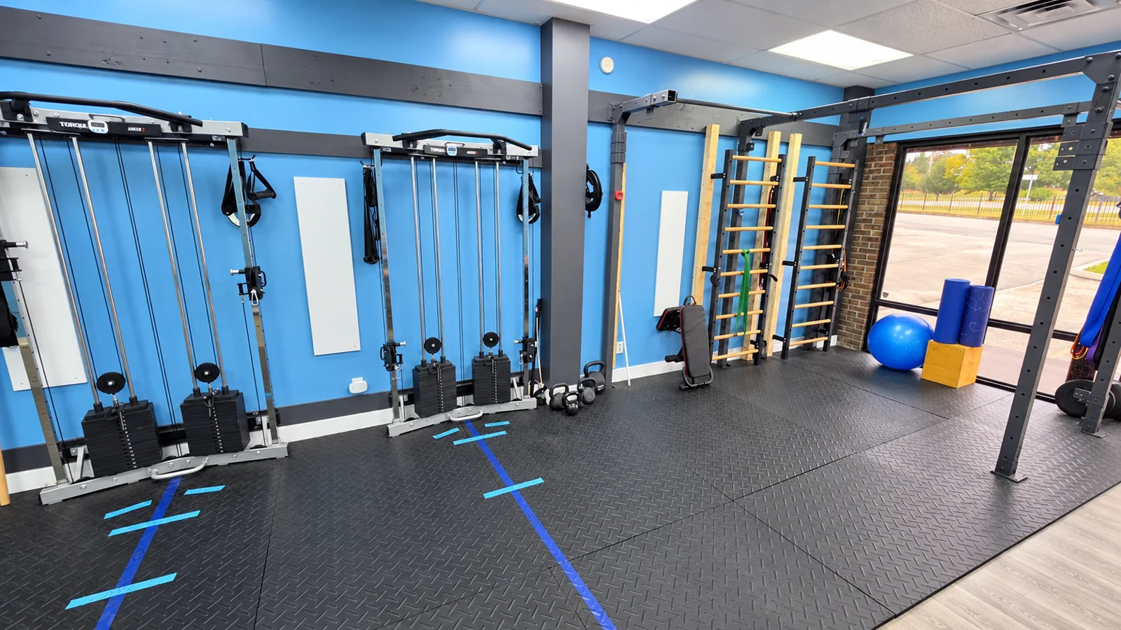 Optimal Fitness training room with cable machines and stall bars